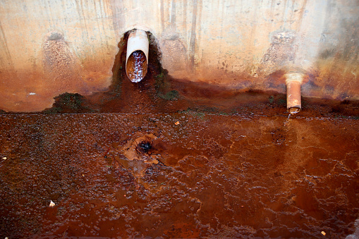 A focus scene on oil stained wall surrounding drainage pipe.