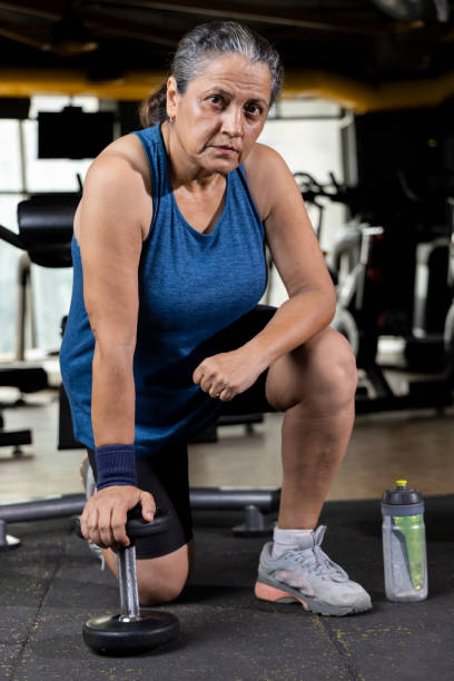 istock Woman kneeling on floor with dumbbell 1427220718