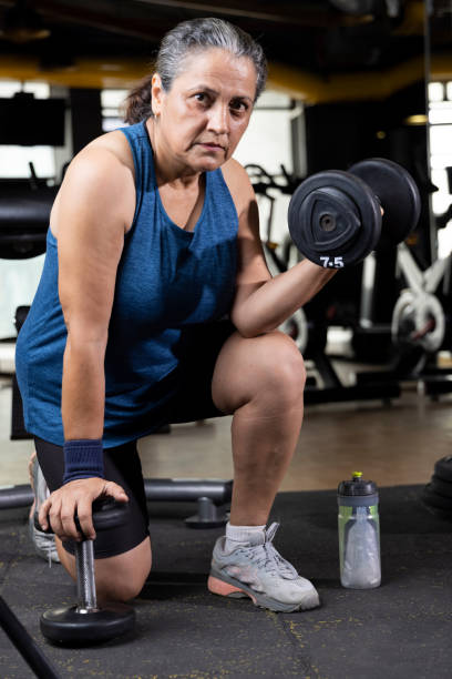 istock Woman kneeling on floor with dumbbell 1427220866