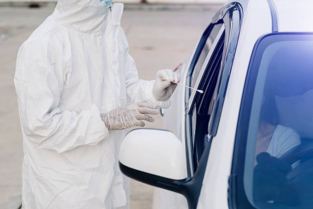 istock Medical worker in protective suit screening woman Driver to Sampling secretion to check for Covid-19. 1427221372