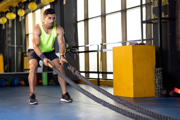 Man training with battle rope in gym gym Active old man in sportswear training with battle rope in gym gym strength training stock pictures, royalty-free photos & images