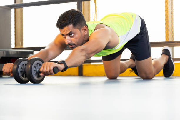 Young man strengthening her body by using the abdominal wheel