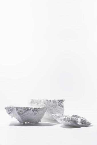 White podiums mockup of styrofoam as abstract snowy cliffs for presentation cosmetics products or goods in sun beam with glare, vertical, copy space. Template stage in rough industrial fashion style.