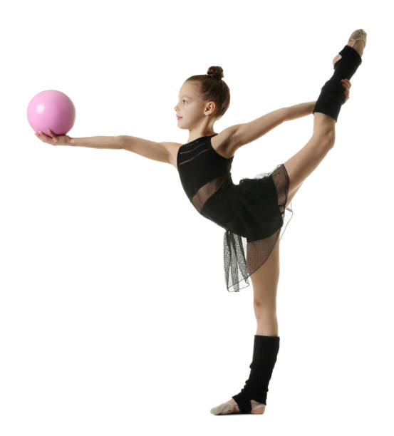 istock Cute little gymnast with ball doing standing split on white background 1427234762