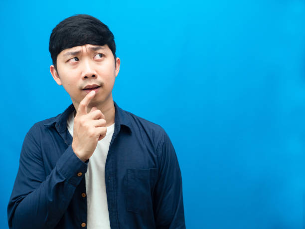 istock Asian man feel doubt and hesitate looking at copy space blue background 1427235637