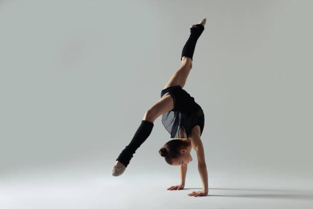 istock Cute little gymnast doing handstand on white background 1427236127