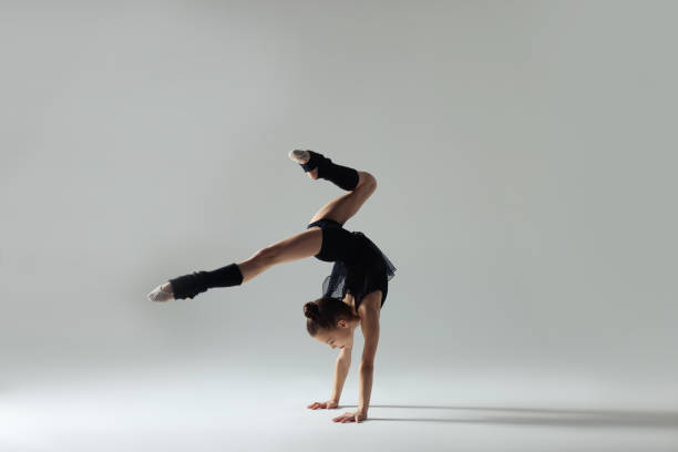 istock Cute little gymnast doing handstand on white background 1427237309