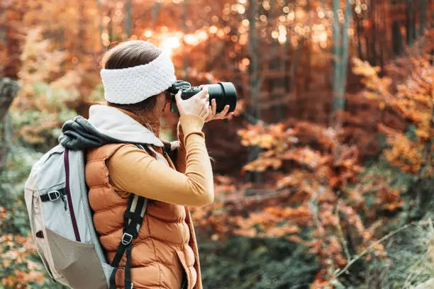 Photo of Young female photographer taking photos in the nature with her camera