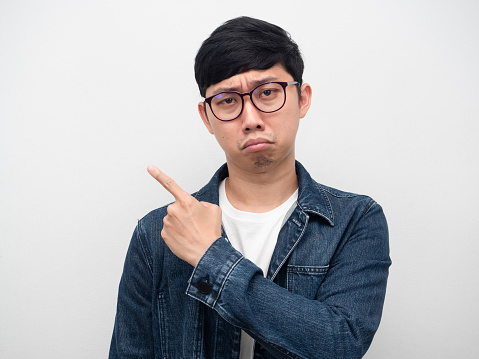 Portrait man wearing glasses jeans shirt sadness emotion point finger isolated