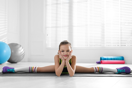 Cute little girl doing gymnastic exercise indoors. Side split