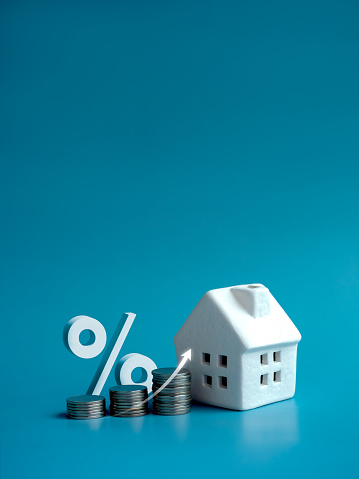 Home tax concept, residential or real estate property, land and building annual taxation. Rise up arrow and percentage icon on coin stack as chart step and white small house model on blue background.