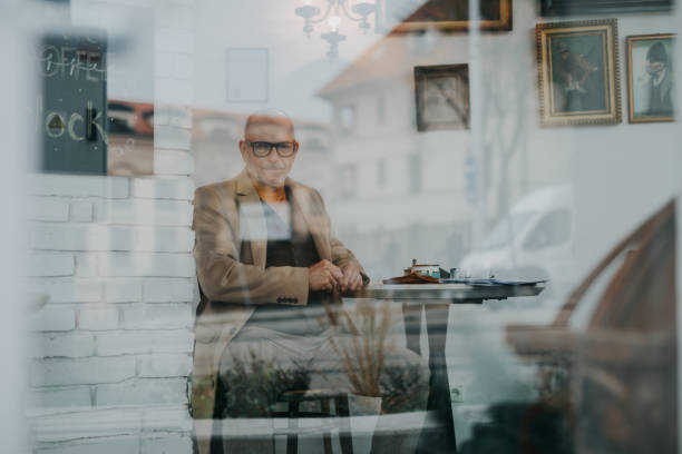 istock Elegant senior man sitting in a cafe and looking at camera. 1427243965