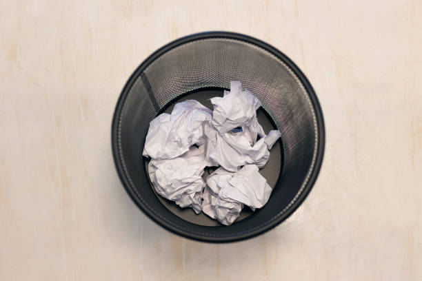 Trash basket with white paper balls.