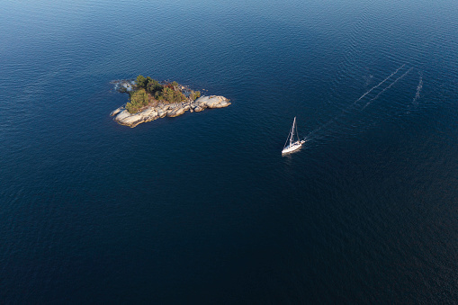 A sailboat passes a small island in the Stockholm archipelago.