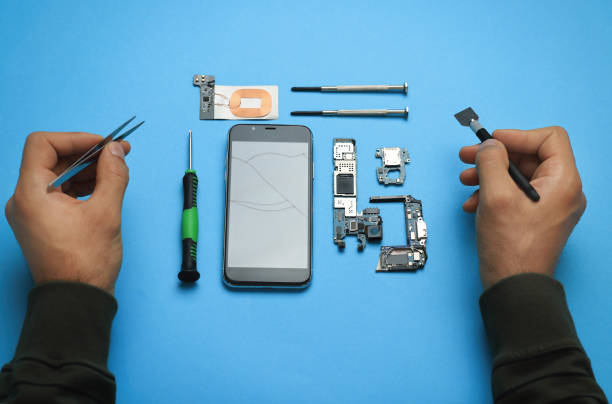 istock Man repairing broken smartphone on light blue background, above view 1427246178