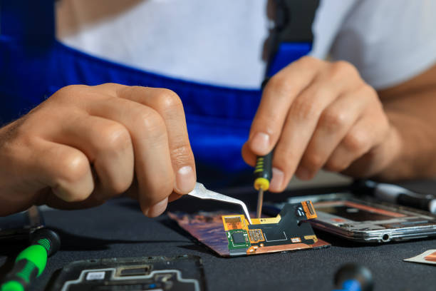 istock Technician repairing broken smartphone at table, closeup 1427246272