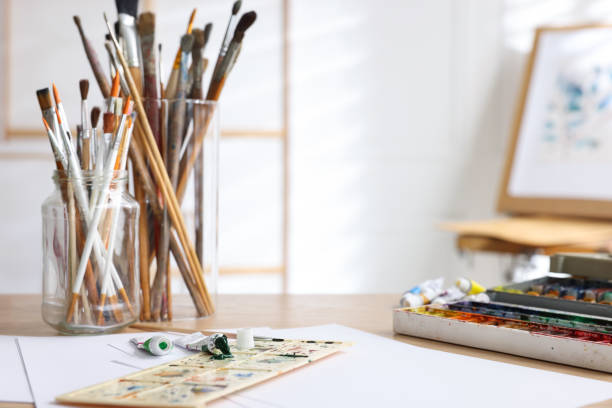 istock Different brushes, paints, palette and paper sheets on wooden table in studio. Space for text 1427246418