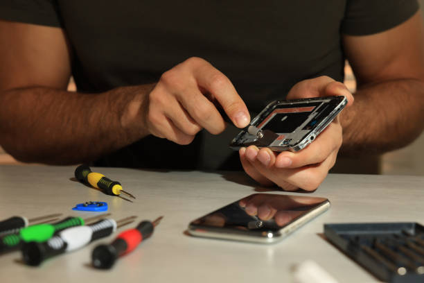 istock Technician repairing broken smartphone at table, closeup 1427246487