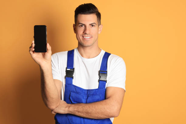 istock Repairman with modern smartphone on orange background 1427246492