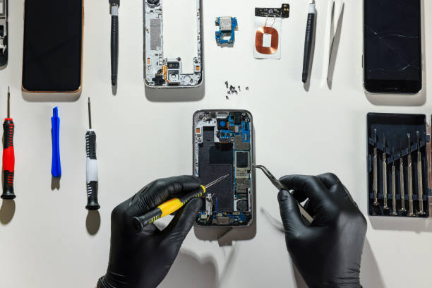 istock Technician repairing broken smartphone at white table, top view 1427246739