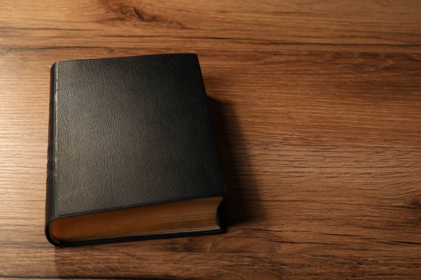 istock Bible with black cover on wooden table. Space for text 1427247133