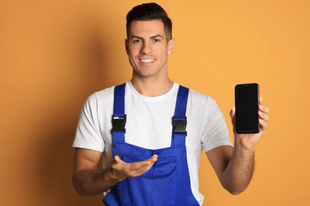 istock Repairman with modern smartphone on orange background 1427247798