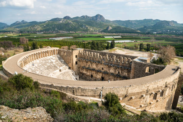 Exterior view of the the Roman antique theatre building at Aspendos ancient site in Turkey Antalya, Turkey - February 9, 2021. Exterior view of the the Roman antique theatre building at Aspendos ancient site in Turkey. It was built in 155 by the Greek architect Zenon. greek amphitheater stock pictures, royalty-free photos & images