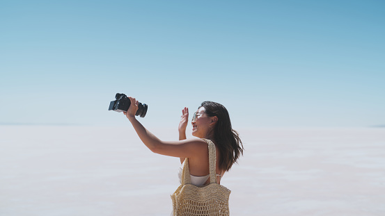 A young female tourist and social media influencer is taking selfies and vlog with a professional camera during her travel on white salt in Salt Lake Türkiye.