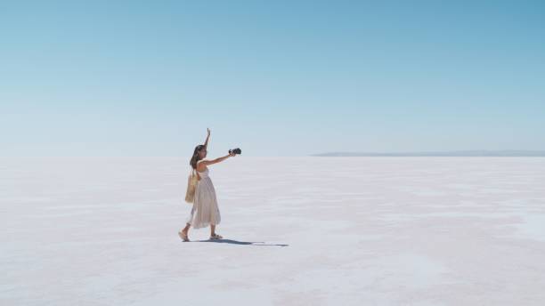 若い女性の観光客やソーシャルメディアのインフルエンサーが、ソルトレーク・トゥルキエの白い塩を旅行中に自撮りやブログを撮っている - lake asia young women beautiful people ストックフォトと画像
