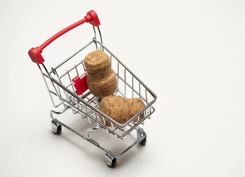 Corks with mini cart supermarket on white background. Concept of delivery, online shopping. Copy space.