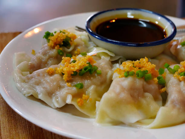 istock Close up Steamed wonton dumpling stuffed with minced pork and shrimp on white plate, serving with chili sesame oil sauce, Asian cuisine, selective focus 1427256715