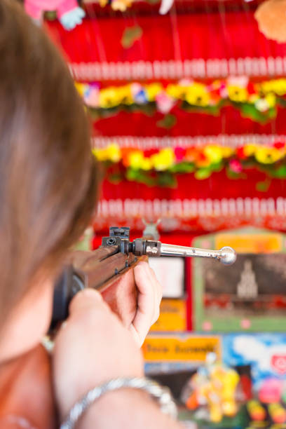 Young man at a amusement park doing some flower shooting at a shooting gallery.