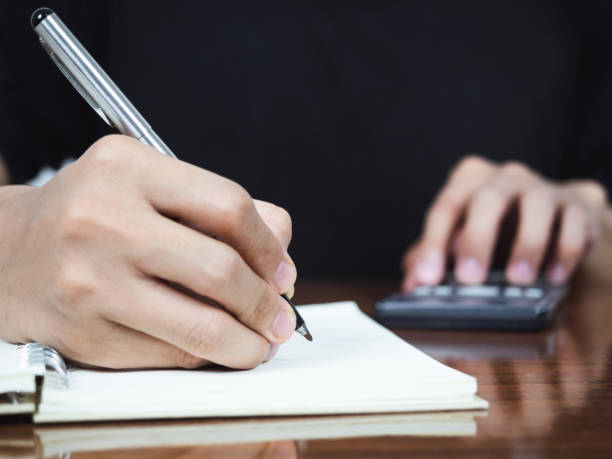 istock Close up hand writing pen for accounting on notebook with using calculator 1427258882