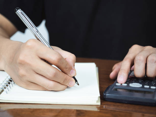 istock Close up hand writing pen for accounting on notebook with using calculator 1427258905
