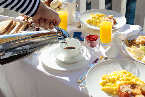 woman eating breakfast in the bed in hotel. Fresh croissant bread fruits in plate. straw hat