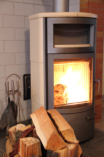 a burning fireplace stove with wood and pellets in the foreground