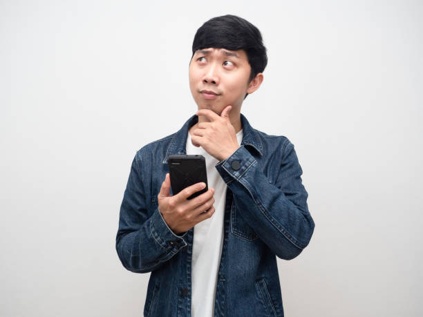 istock Young man jeans shirt holding smartphone gesture thinking 1427259344