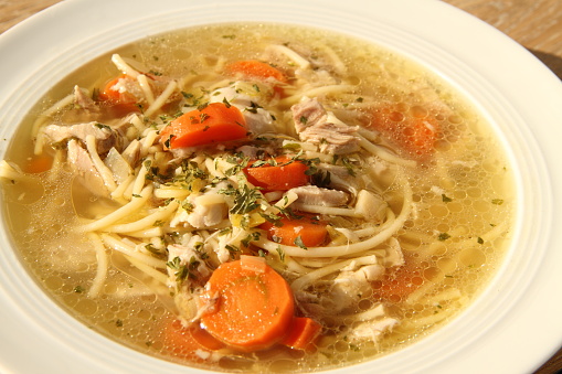 a delicious chicken soup with carrots on the table as a background