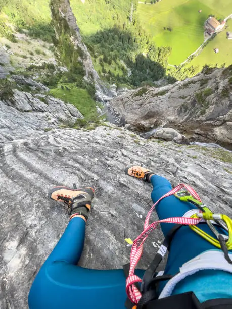 Photo of POV of woman on via ferrata, vertical cliff drop view