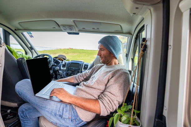 Young man studying in a van, on the move learning concept