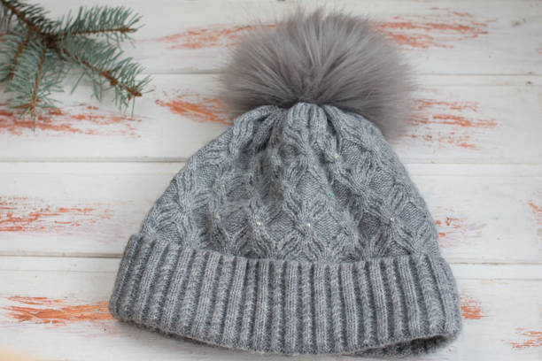 Women's winter warm knitted hat with a pompom. Green spruce twig