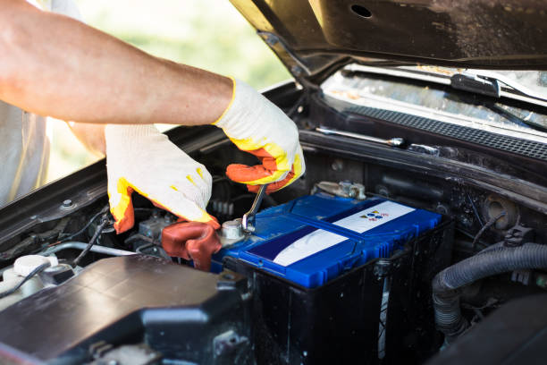 sostituzione della batteria in un'auto. il meccanico svita gli elementi di fissaggio della batteria con un cacciavite - battery replacement foto e immagini stock