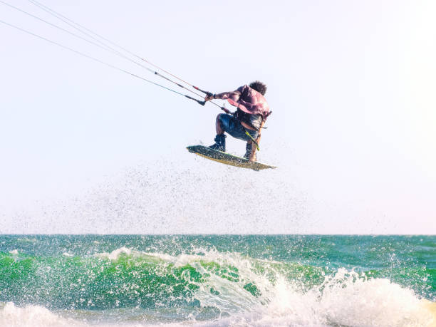 Young man kite boarder jumps over the sea at sunset. Selective focus.