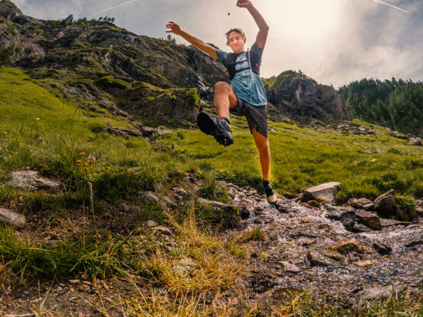 istock Man trail runner jumping water stream 1427276133