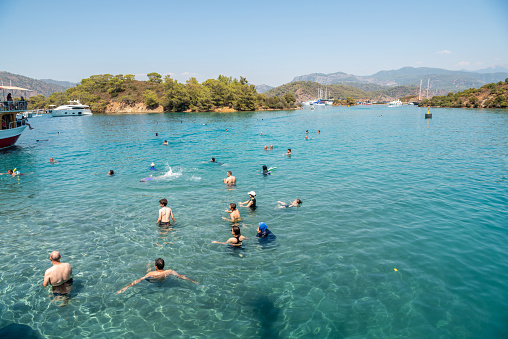 Fethiye, Turkey - August 21, 2021. Tourists bathing along the coastline of Yassica Adalari islands off Gocek coast in Mugla province of Turkey.