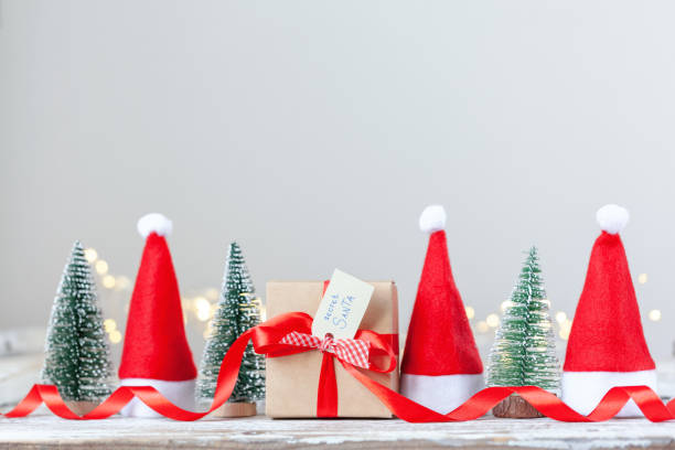 Christmas white box or present with red ribbon from Secret Danta with santa hat and xmas trees. Happy holiday concept. stock photo