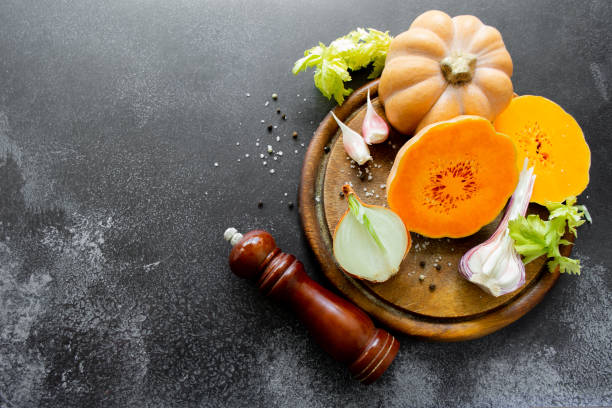 istock Vegetables: orange squash, garlic, onions. Spice mill, pepper, salt. Black background. Copy space 1427281119
