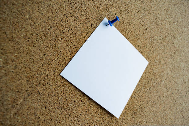 gros plan d’une note de papier blanc sur un panneau de liège, attaché avec une épingle bleue. espace de copie - clipboard blank paper pinning photos et images de collection