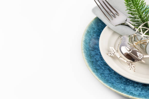 Festive Christmas and New year table setting with holiday decor on a white background with copy space. Holiday card with Christmas setting suitable for New year menu. Soft focus stile, close up