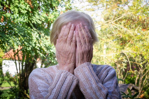 old woman covering her face with her hands